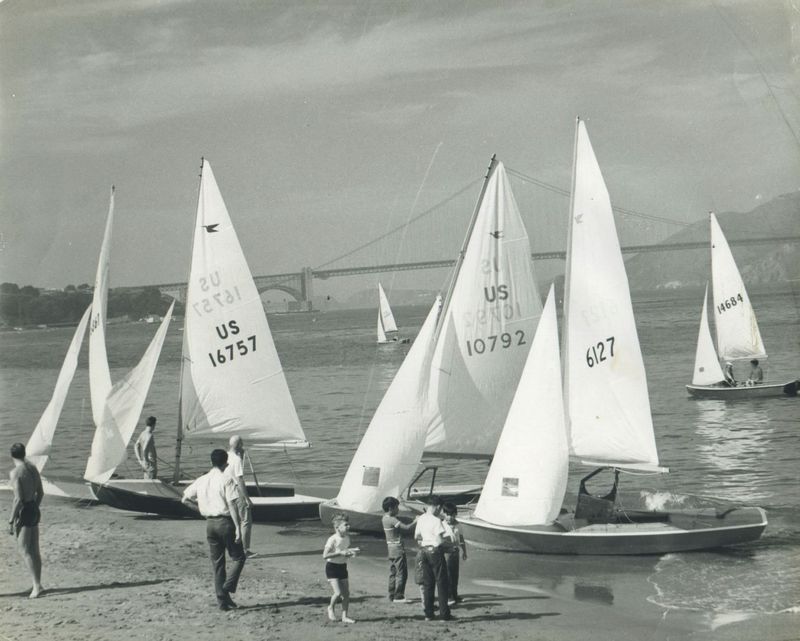 Snipes pulled up on the beach with the Golden Gate Bridge behind, sailors and kids gathered on the sand