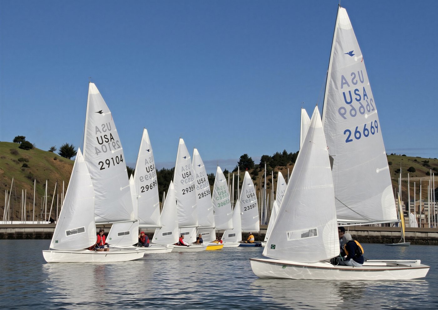 A line of Snipes sailing on the Bay under a blue sky